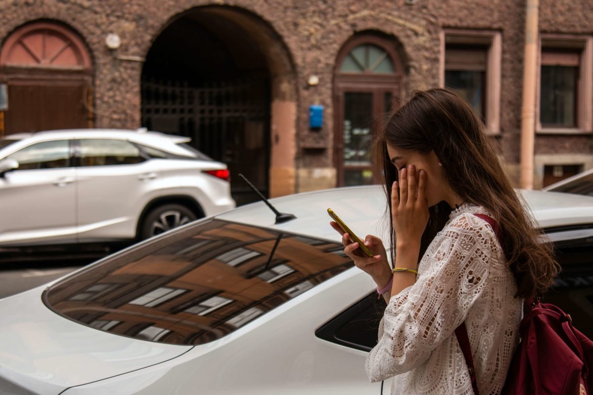 person standing next to car on a cell phone
