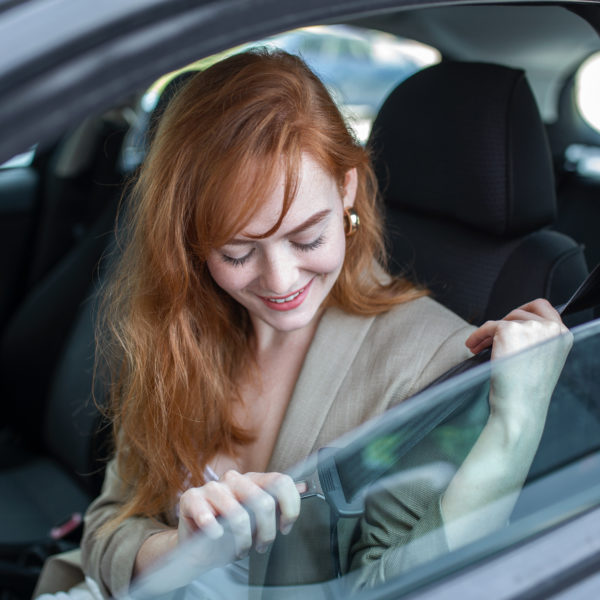 Safety first. Beautiful Caucasian lady fastening car seat belt. Pretty young woman driving her new car. Pretty young woman driving her new car. Female fastening safety belt in car