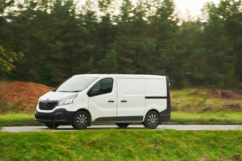 A white van with a blank wrap for your business branding and delivery service. Isolated mockup of a commercial vehicle on the road.