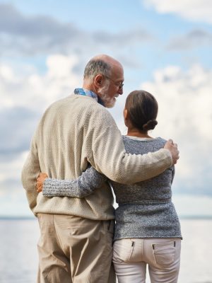 Embracing seniors having talk by seaside during vacation on summer resort